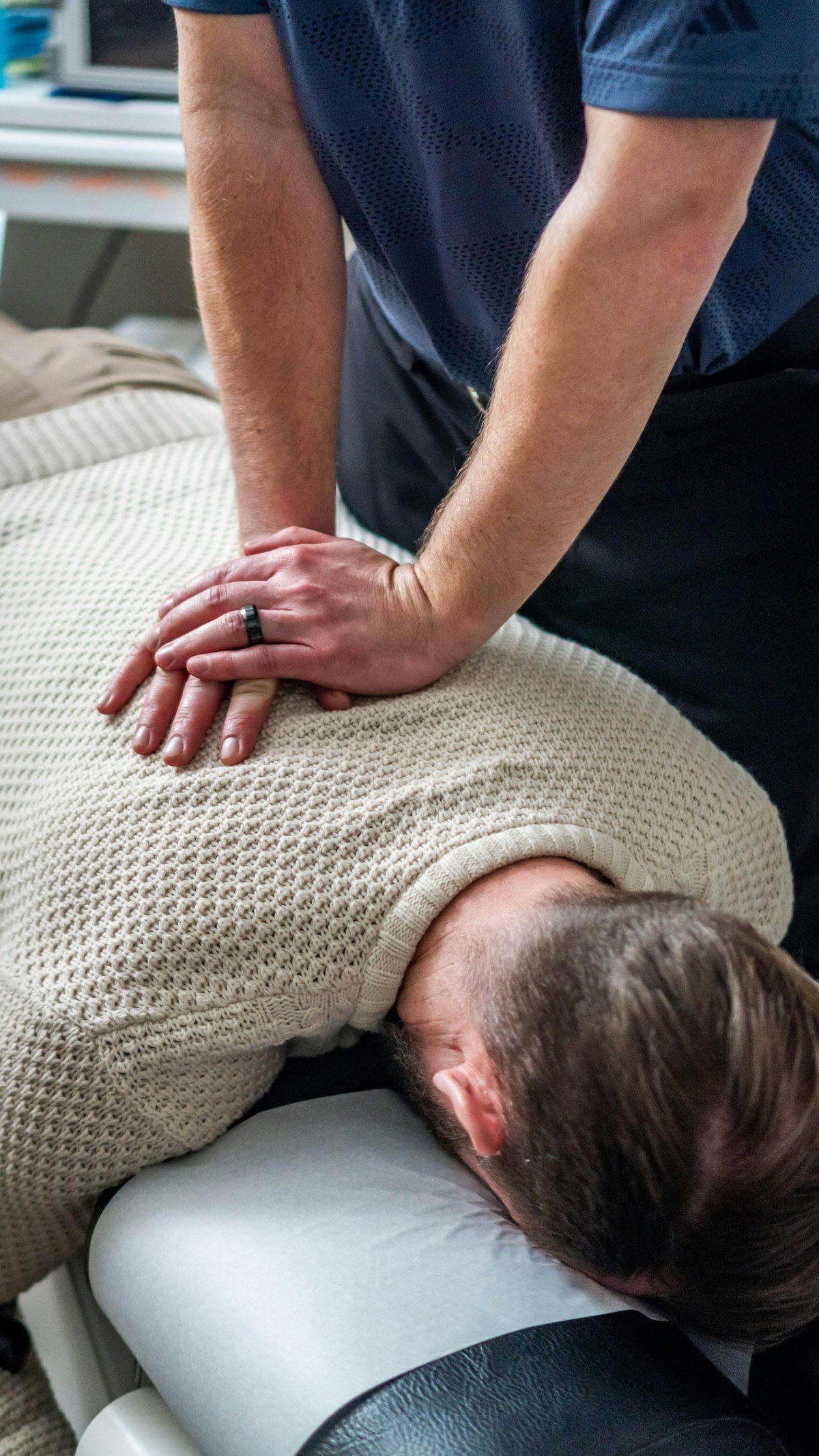 Thérapeute travaillant le haut du dos et la nuque d’un patient allongé
